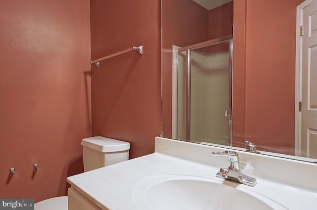 bathroom with toilet, a stall shower, and vanity