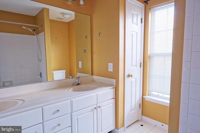 bathroom with double vanity, a shower, tile patterned floors, and toilet