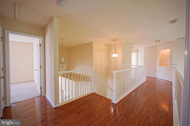 corridor with an upstairs landing, hardwood / wood-style floors, and baseboards