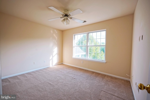 carpeted spare room featuring baseboards and ceiling fan
