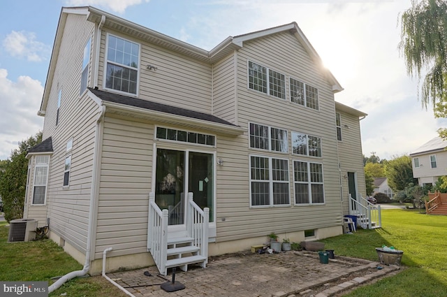 rear view of house featuring entry steps, a lawn, and cooling unit