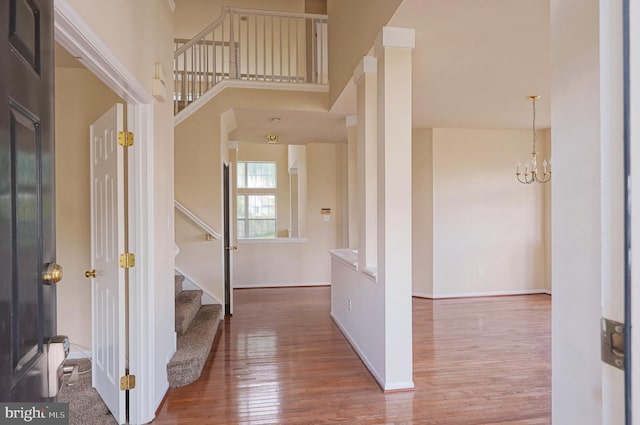 entryway with wood finished floors, stairs, baseboards, and a chandelier