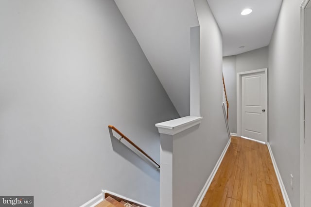 hallway featuring an upstairs landing, light wood-style flooring, and baseboards