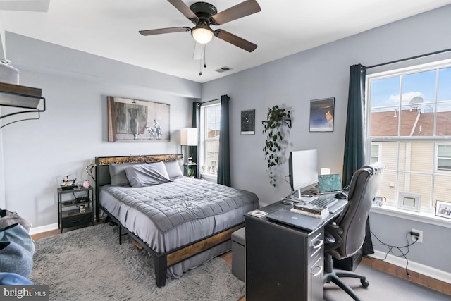 bedroom featuring wood finished floors, baseboards, and multiple windows