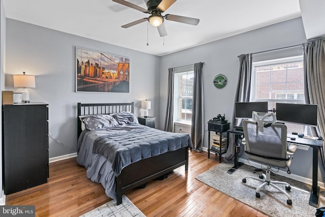 bedroom featuring wood-type flooring, baseboards, a desk, and ceiling fan
