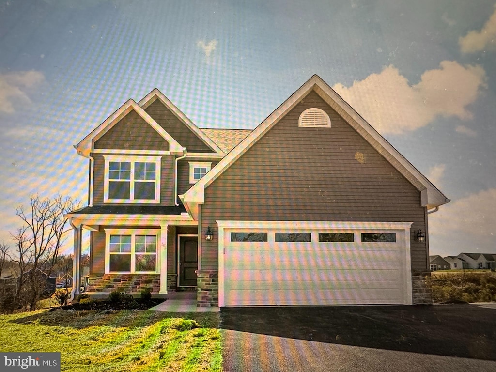 craftsman inspired home with a garage, stone siding, and driveway