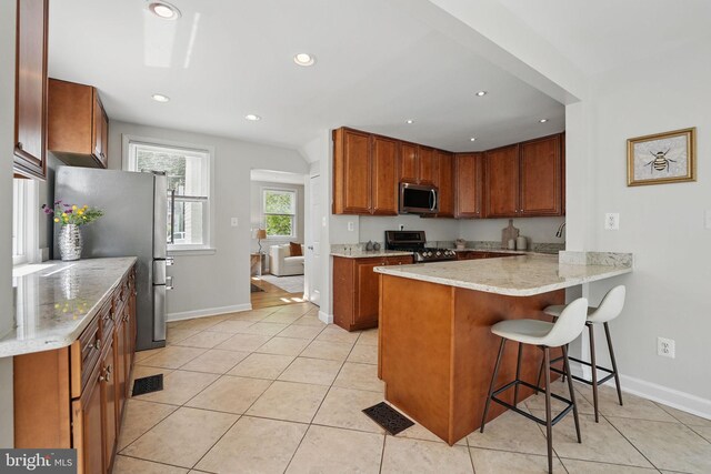 6924 Jefferson Ave, Falls Church, VA 22042 - kitchen featuring appliances with stainless steel finishes, a peninsula, a kitchen breakfast bar, light tile patterned flooring, and recessed lighting