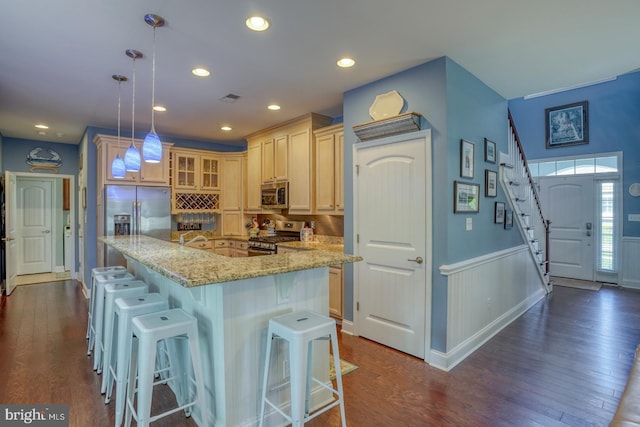20785 Rodney Dr, Rehoboth Beach, DE 19971 - kitchen featuring appliances with stainless steel finishes, glass insert cabinets, dark wood-style flooring, wainscoting, and a kitchen bar