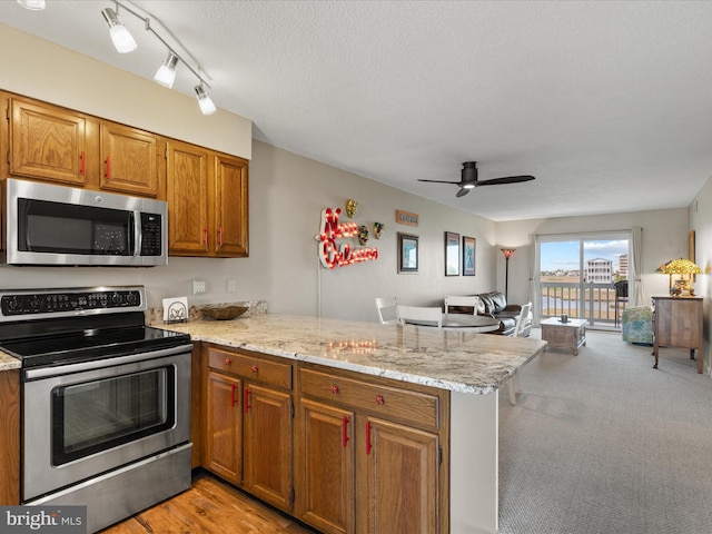 117 76th St Unit 302, Ocean City, MD 21842 - kitchen featuring appliances with stainless steel finishes, a peninsula, ceiling fan, light stone countertops, and open floor plan