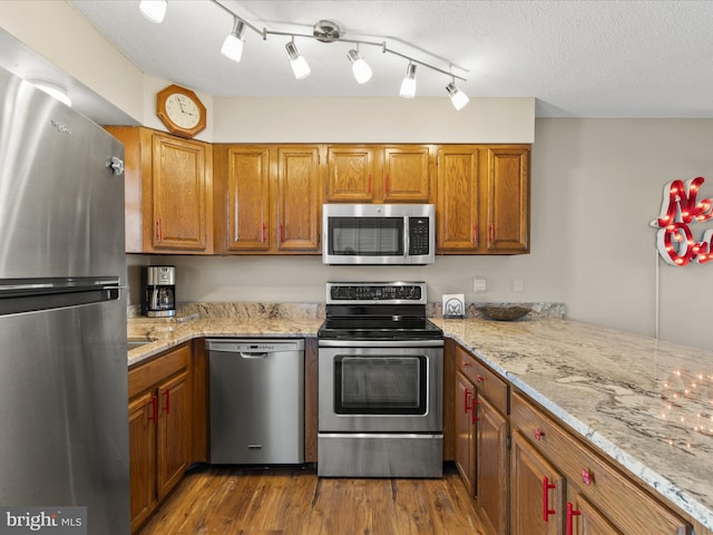 117 76th St Unit 302, Ocean City, MD 21842 - kitchen with appliances with stainless steel finishes, wood finished floors, light stone countertops, and brown cabinets