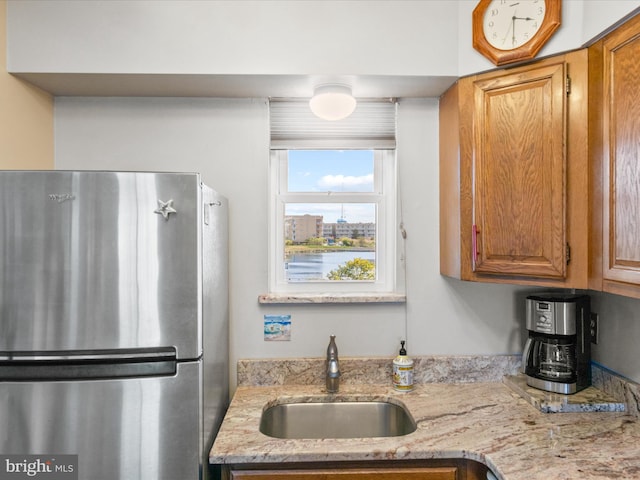 117 76th St Unit 302, Ocean City, MD 21842 - kitchen with freestanding refrigerator, a sink, light stone countertops, and brown cabinetry
