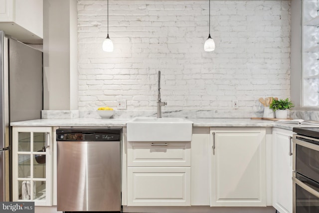 223 Parker St NE, Washington, DC 20002 - kitchen featuring stainless steel appliances, a sink, brick wall, white cabinetry, and light stone countertops