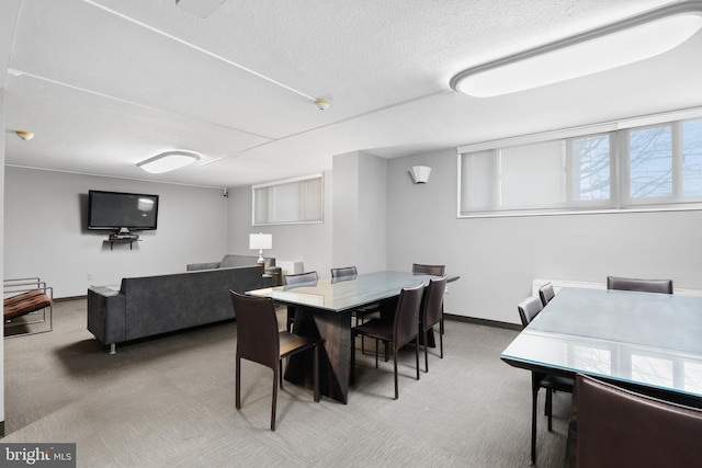 carpeted dining area featuring baseboards, plenty of natural light, and a textured ceiling