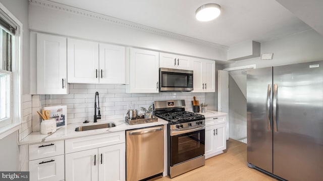 7913 Charlesmont Rd, Baltimore, MD 21222 - kitchen with appliances with stainless steel finishes, a sink, white cabinetry, backsplash, and light wood-style floors
