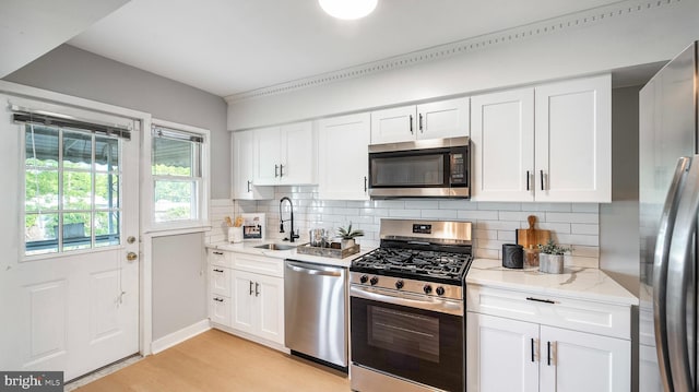 7913 Charlesmont Rd, Baltimore, MD 21222 - kitchen with stainless steel appliances, a sink, backsplash, light wood-style floors, and white cabinetry