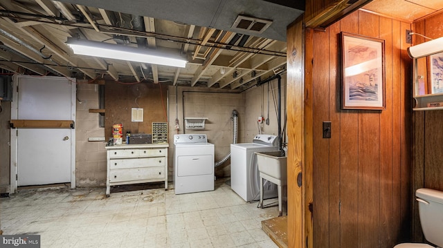 7913 Charlesmont Rd, Baltimore, MD 21222 - laundry area with washer and clothes dryer, concrete block wall, wood walls, and light flooring