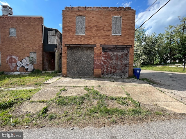 back of house featuring a garage, concrete driveway, and brick siding