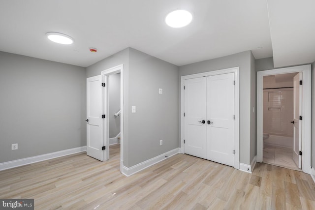 unfurnished bedroom with light wood-type flooring, baseboards, and a closet