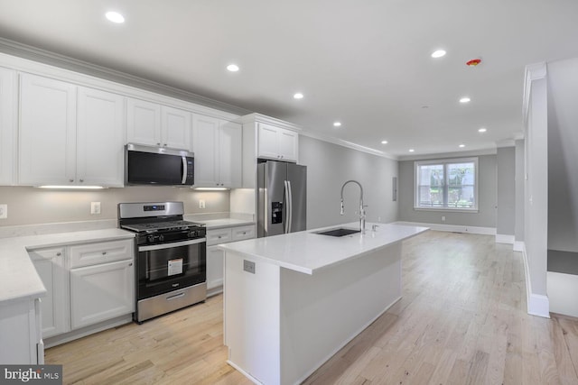 kitchen with appliances with stainless steel finishes, a sink, ornamental molding, white cabinetry, and light countertops