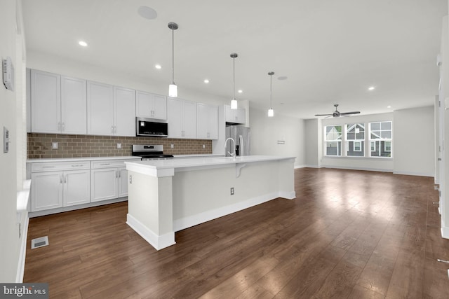 1552 Meadowlark Glen Rd, Dumfries, VA 22026 - kitchen with appliances with stainless steel finishes, decorative backsplash, ceiling fan, dark wood-type flooring, and a center island with sink