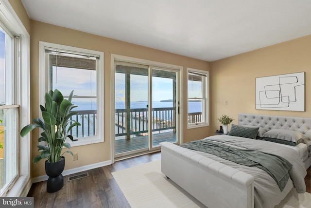bedroom featuring access to outside, baseboards, dark wood-type flooring, and a water view