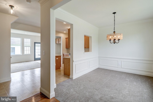spare room with light colored carpet, crown molding, a chandelier, a wainscoted wall, and recessed lighting