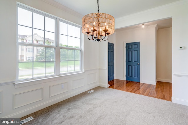 empty room with carpet, crown molding, a chandelier, and wainscoting