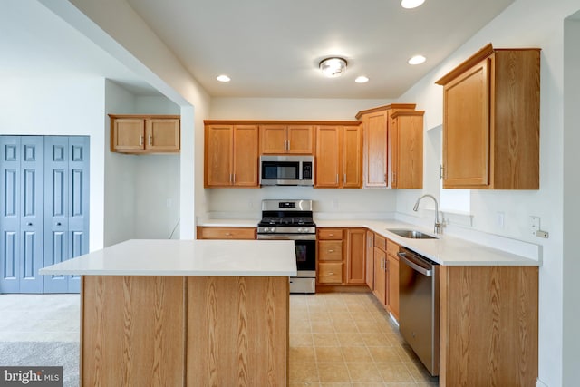 kitchen with appliances with stainless steel finishes, a sink, light countertops, recessed lighting, and a center island