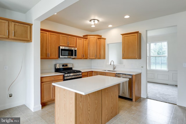 kitchen with stainless steel appliances, a sink, light countertops, a kitchen island, and recessed lighting