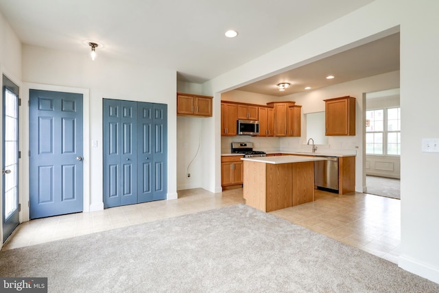 kitchen with appliances with stainless steel finishes, a kitchen island, light tile patterned floors, light countertops, and brown cabinetry