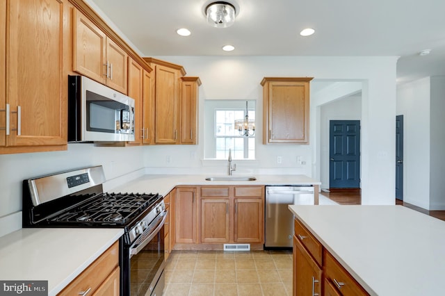 kitchen with appliances with stainless steel finishes, a sink, recessed lighting, light countertops, and a chandelier