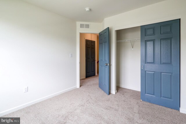 unfurnished bedroom featuring light colored carpet, a closet, and baseboards