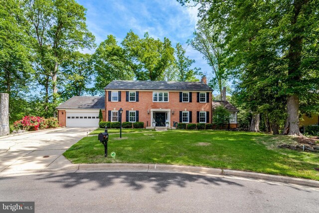 104 River Forest Ln, Fort Washington, MD 20744 - colonial inspired home with driveway, a chimney, a garage, brick siding, and a front yard