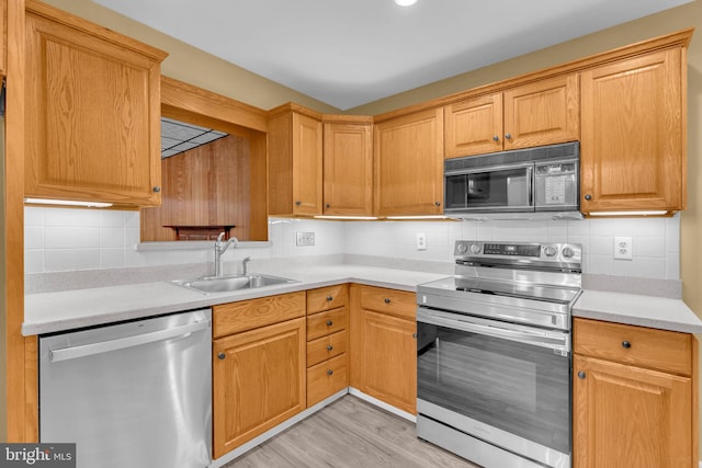 kitchen featuring appliances with stainless steel finishes, a sink, light countertops, and decorative backsplash