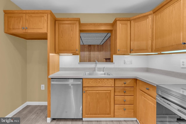 kitchen featuring dishwasher, a sink, light countertops, decorative backsplash, and light wood-type flooring