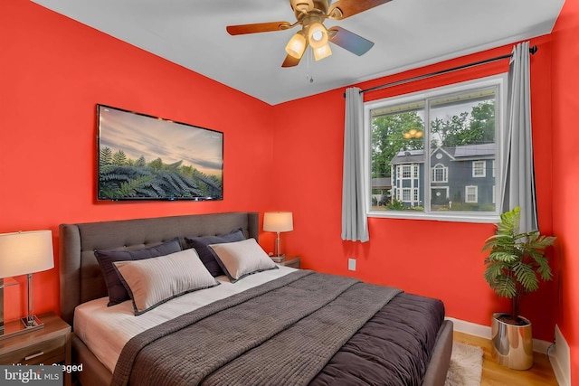 bedroom with baseboards, wood finished floors, and a ceiling fan