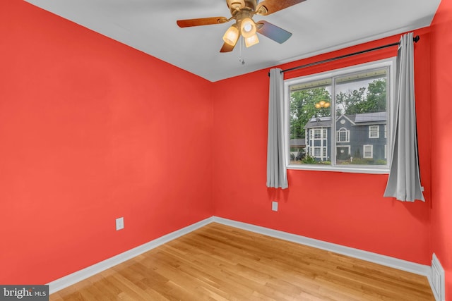 spare room featuring baseboards, wood finished floors, and ceiling fan