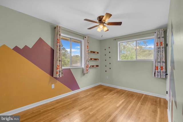 empty room with baseboards, wood finished floors, and ceiling fan