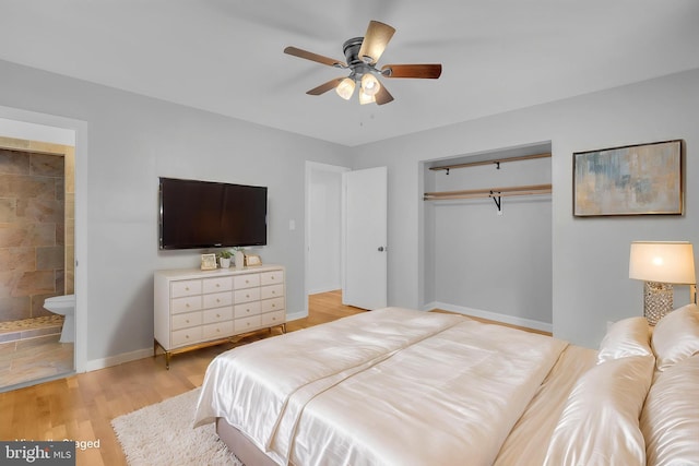 bedroom featuring a closet, light wood finished floors, ensuite bathroom, baseboards, and ceiling fan