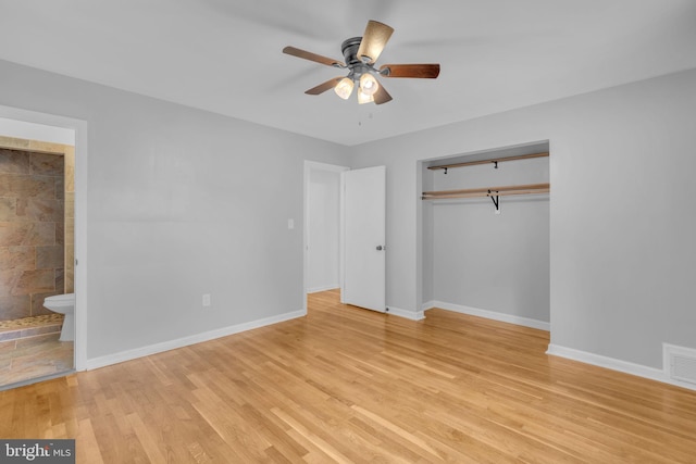 unfurnished bedroom with a closet, light wood-style flooring, baseboards, connected bathroom, and a ceiling fan