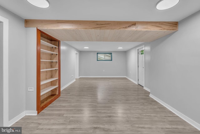 basement featuring light wood-style flooring, built in features, and baseboards