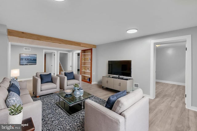 living area featuring light wood finished floors, stairway, and baseboards
