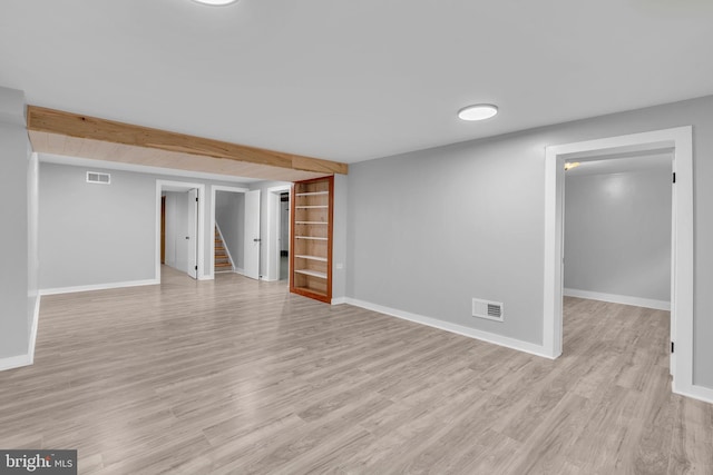 finished basement featuring stairs, light wood-type flooring, and baseboards