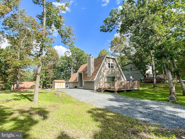 view of front of house with a storage unit, a wooden deck, an outdoor structure, a chimney, and a front yard