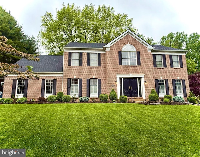 colonial inspired home featuring a front yard and brick siding