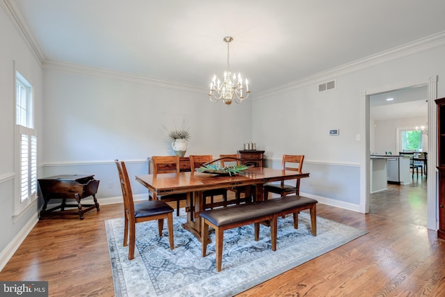 dining room featuring a chandelier, ornamental molding, wood finished floors, and baseboards