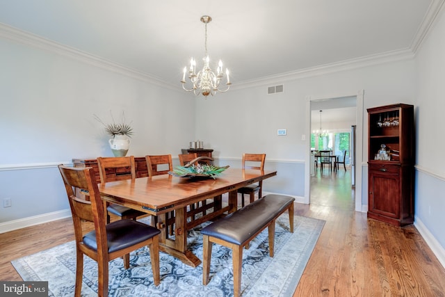 dining room with a chandelier, ornamental molding, light wood-type flooring, and baseboards