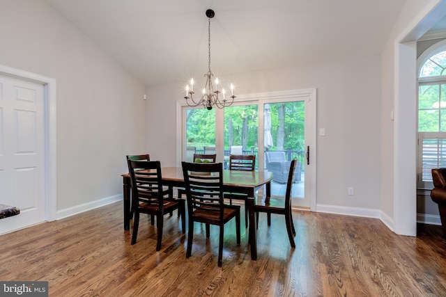 dining space featuring a chandelier, wood finished floors, baseboards, and vaulted ceiling