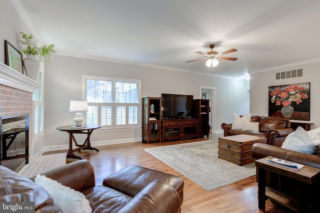living room with a fireplace, a ceiling fan, wood finished floors, crown molding, and baseboards