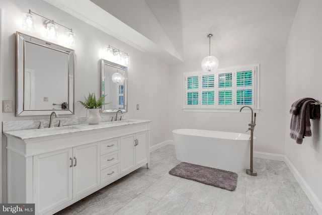 full bathroom featuring marble look tiles, double vanity, a freestanding bath, baseboards, and lofted ceiling